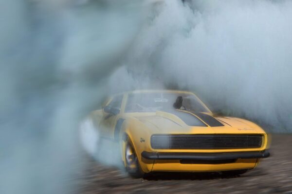 classic yellow and black sports car drifting on road with smoke